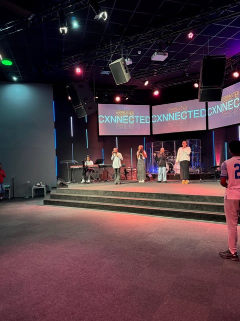 Stage performance at Connected conference with band playing on elevated platform under colorful stage lights and pink signage